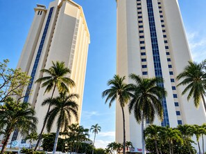 Two tall buildings with a clear sky, surrounded by palm trees. - Beautiful Oceanfront Suite in the Heart of Acapulco (Acapulco de Juárez)