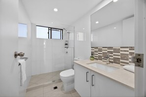 Un bagno moderno dotato di doccia, WC e lavandino.
