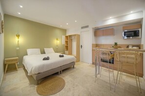 A bedroom with a bed, bedside tables, and a small kitchenette with a microwave. - 15398910 FRGK Private Townhouse HQ: Walking Distance to the Palais (Cannes)