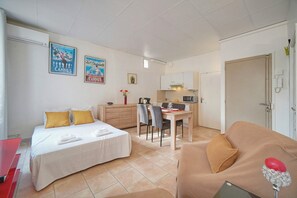 A hotel room with a bed, a desk, a chair, a couch, and a kitchenette. - Frgk Clemenceau 1-Bedroom Beach Apartment with UltraFast Wi-Fi (Cannes)