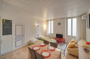 Quarto de hotel com mesa de jantar posta para dois, cama, televisão e sofá.