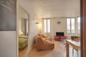 Quarto com cama, sofá, escrivaninha e televisão.