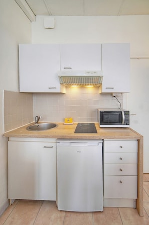 Cozinha compacta com micro-ondas integrado, pia e lava-louças compacta.