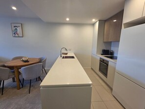 Een moderne keuken met een centraal eiland, een eettafel met stoelen en een inbouwoven.