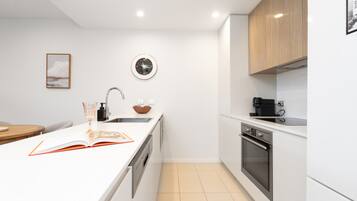 A modern kitchen with white cabinetry, a built-in oven, and a wall-mounted clock.