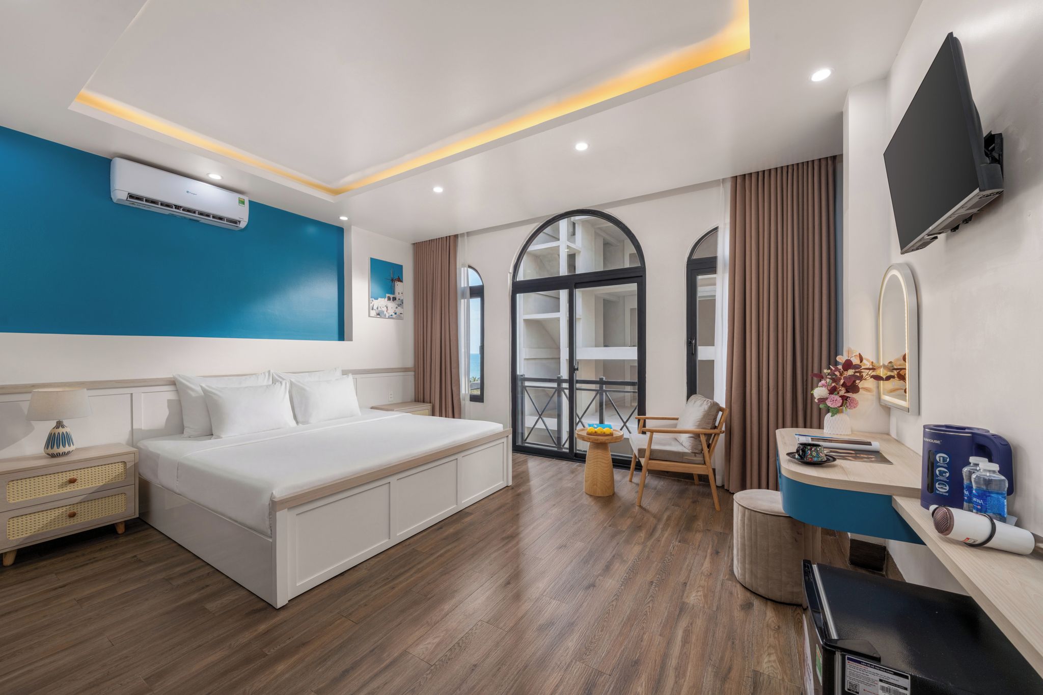 A modern hotel room with a bed, bedside table, and a desk area.