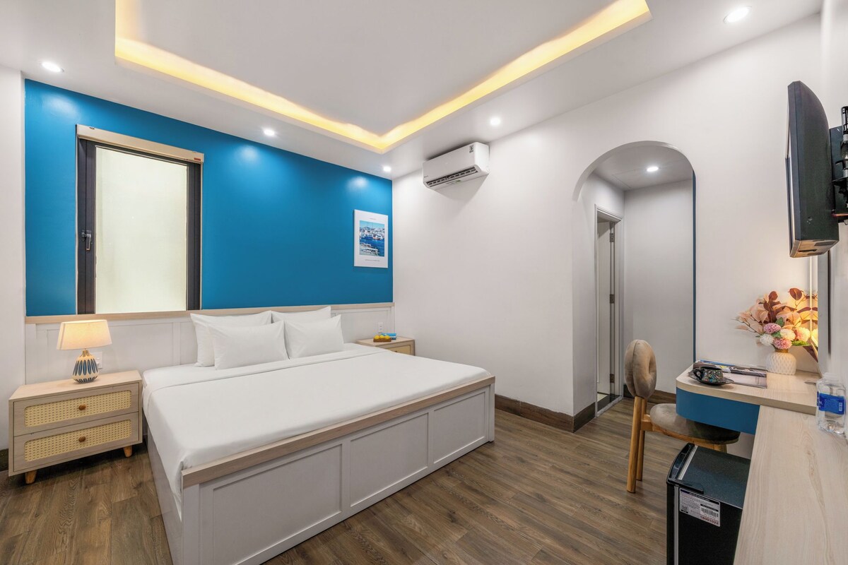 A modern bedroom with a large bed, bedside tables, a desk, and a TV.