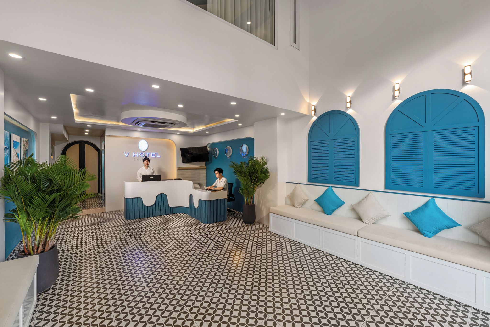 A hotel reception area with a modern design, featuring a reception desk, seating area, and decorative wall elements.