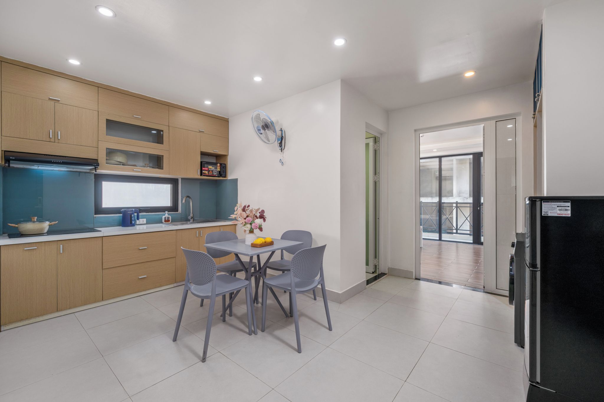 A modern kitchen with a dining area, a built-in oven, and a refrigerator.