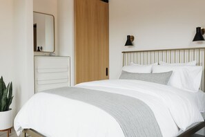 Ein Schlafzimmer mit einem Bett, Nachttischlampen, einem Schminktisch und einem Spiegel.