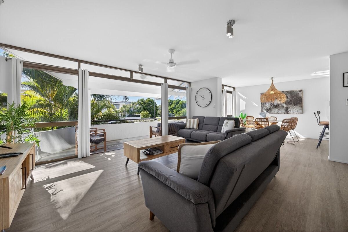 A modern living room with a sofa, coffee table, and a large window with a view of greenery.
