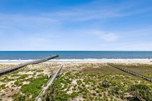 A beach with a wooden boardwalk leading to a pier extending into the ocean. - Comfy Upper Unit Condo To Enjoy The Beach Or The Fishing 2 Bedroom Condo (Fernandina Beach)