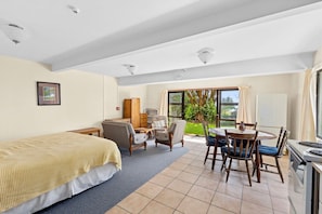 A hotel room with a bed, seating area, and a dining table. - Parapara Esplanade Stay (Takaka)