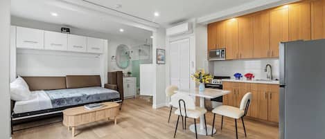Een compacte leefruimte met een bed, een eethoekje, een kitchenette en een badkamer.