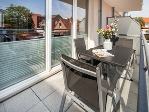 A balcony with a table, chairs, and a vase of flowers. - Holiday Apartment in Norderney With Wi-fi (Norderney)