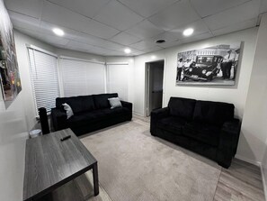 A living room with two black sofas, a wooden coffee table, and a wall-mounted picture. - Grand Bella | Whole House 5BR | Sleeps 14 | Falls (Niagara Falls)