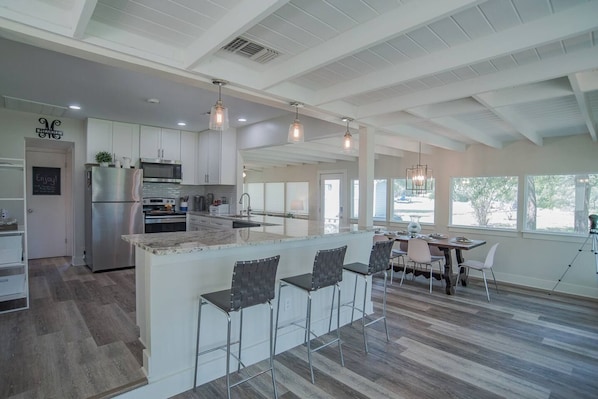 A spacious kitchen with a central island, bar stools, and a dining area with a view.