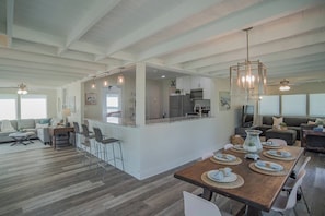 A spacious living area with a kitchen island, dining table, and seating arrangements.