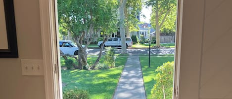 Puerta blanca que ofrece vista a una calle residencial, una acera y un área con césped.