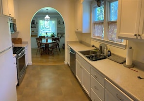 A kitchen with a dining area, a sink, and a window with curtains.