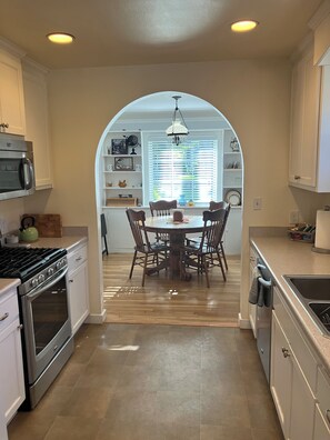 A kitchen with a central island, a dining table with chairs, and a window with blinds.