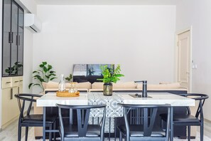 Ein Essbereich mit Tisch, Stühlen, einer Couch und einer Küchenzeile mit Schränken sowie einer Klimaanlage.
