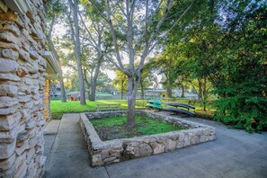 A stone wall, a tree, a grassy area, and a row of canoes. - Fish Haus-Seguin Texas (Seguin)