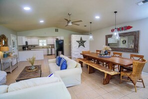 Un amplio espacio de estar con una mesa de comedor, sofás y una cocina al fondo.