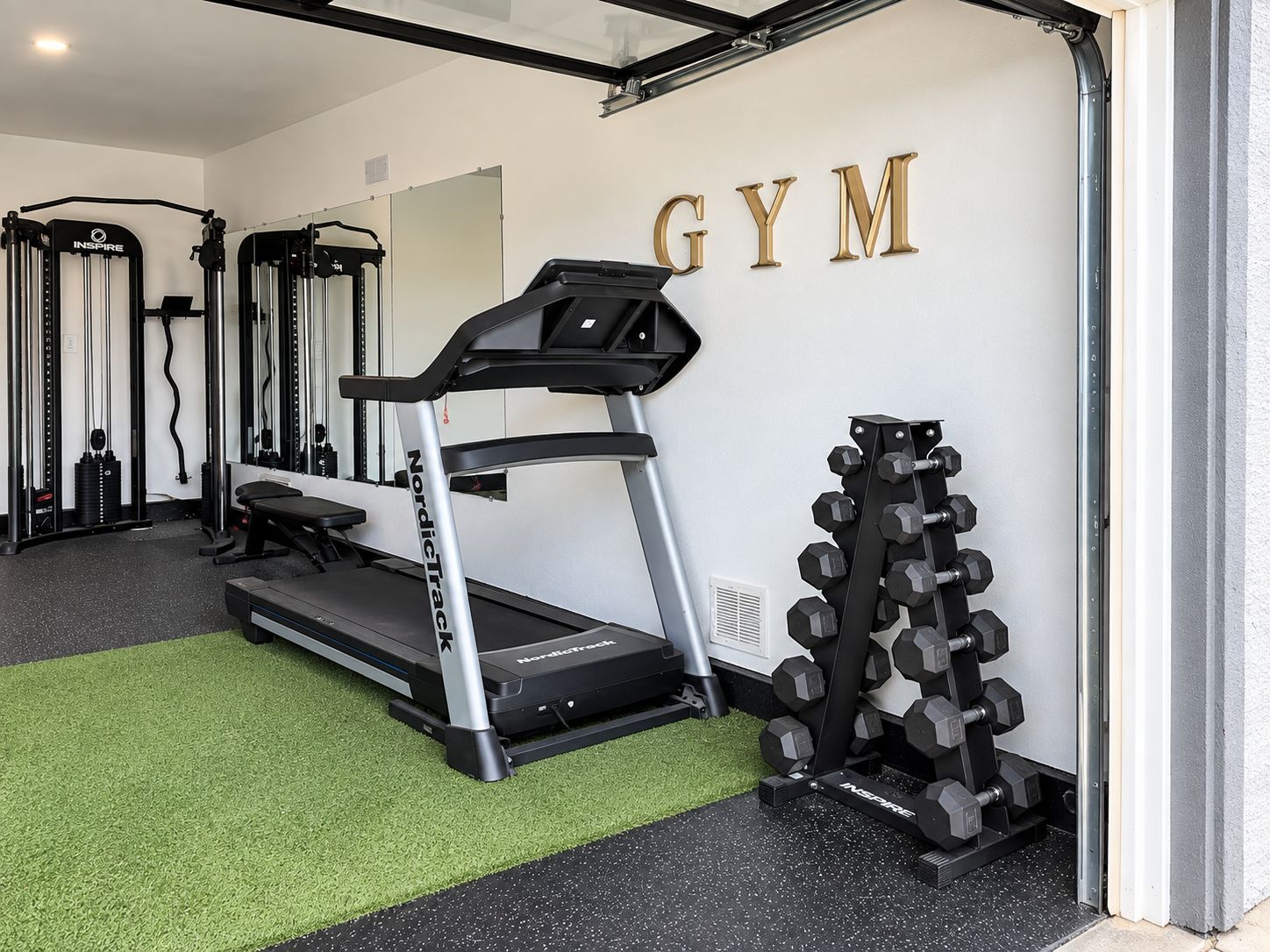 A gym with a treadmill, weight bench, and dumbbells.