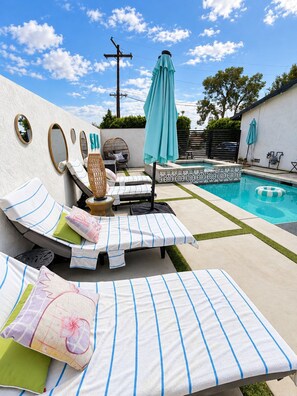 Un espace aménagé au bord de la piscine, avec des chaises longues, une petite table et un mur décoratif.