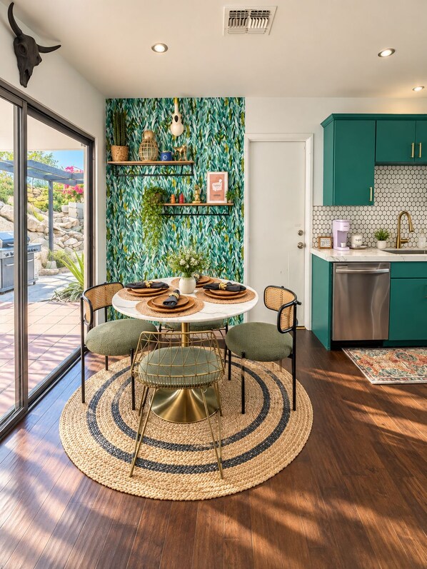 Une cuisine moderne avec des meubles de couleur turquoise, un lave-vaisselle en acier inoxydable et une table de salle à manger ronde, assortie de chaises.