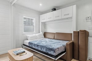 Habitació petita amb un llit, una taula i una finestra.
