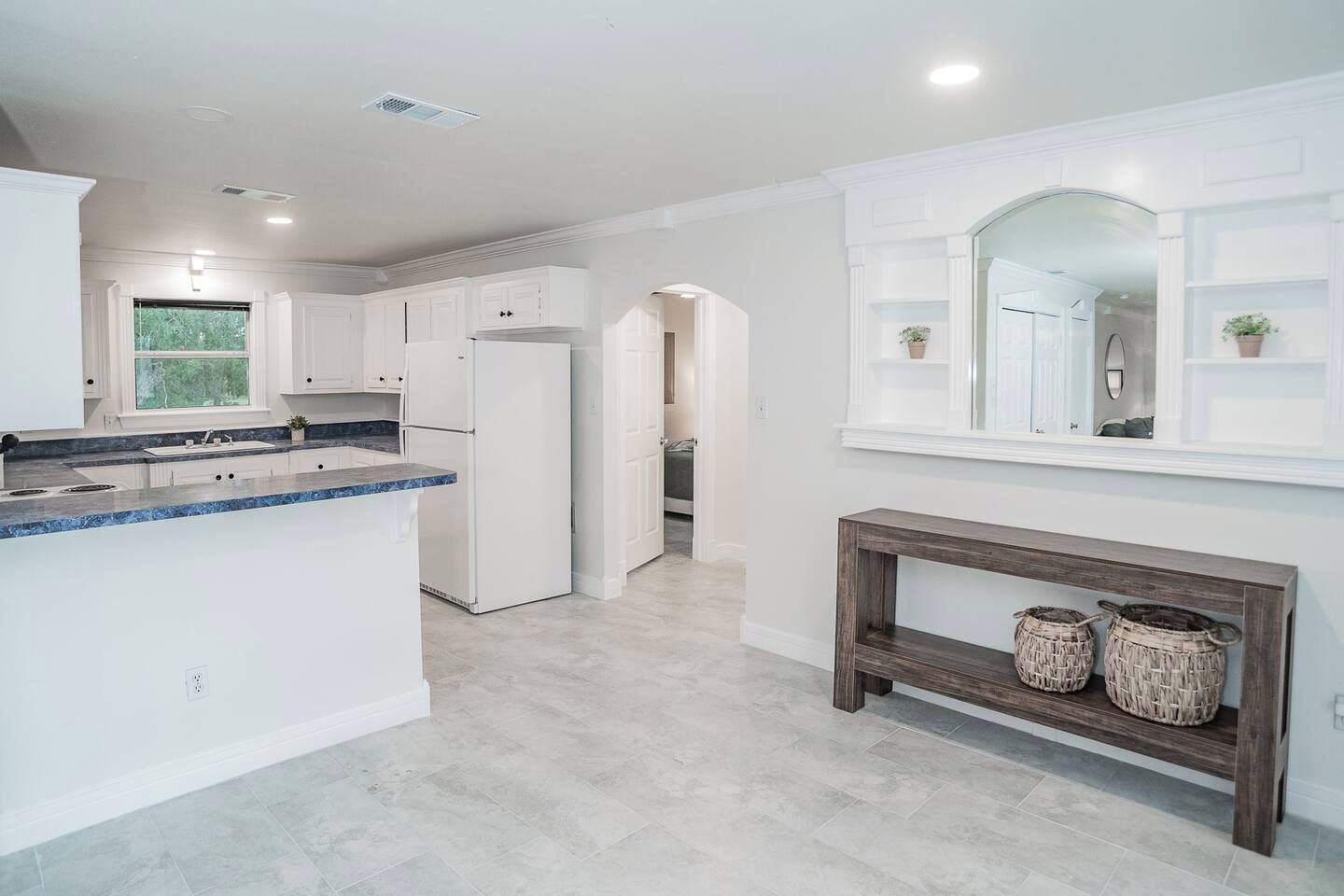 A modern kitchen with white cabinetry, a granite countertop, and a built-in refrigerator.