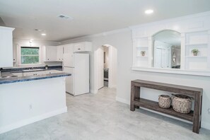 A modern kitchen with white cabinetry, a granite countertop, and a built-in refrigerator. - Bergamot House-Luling Texas (Luling)