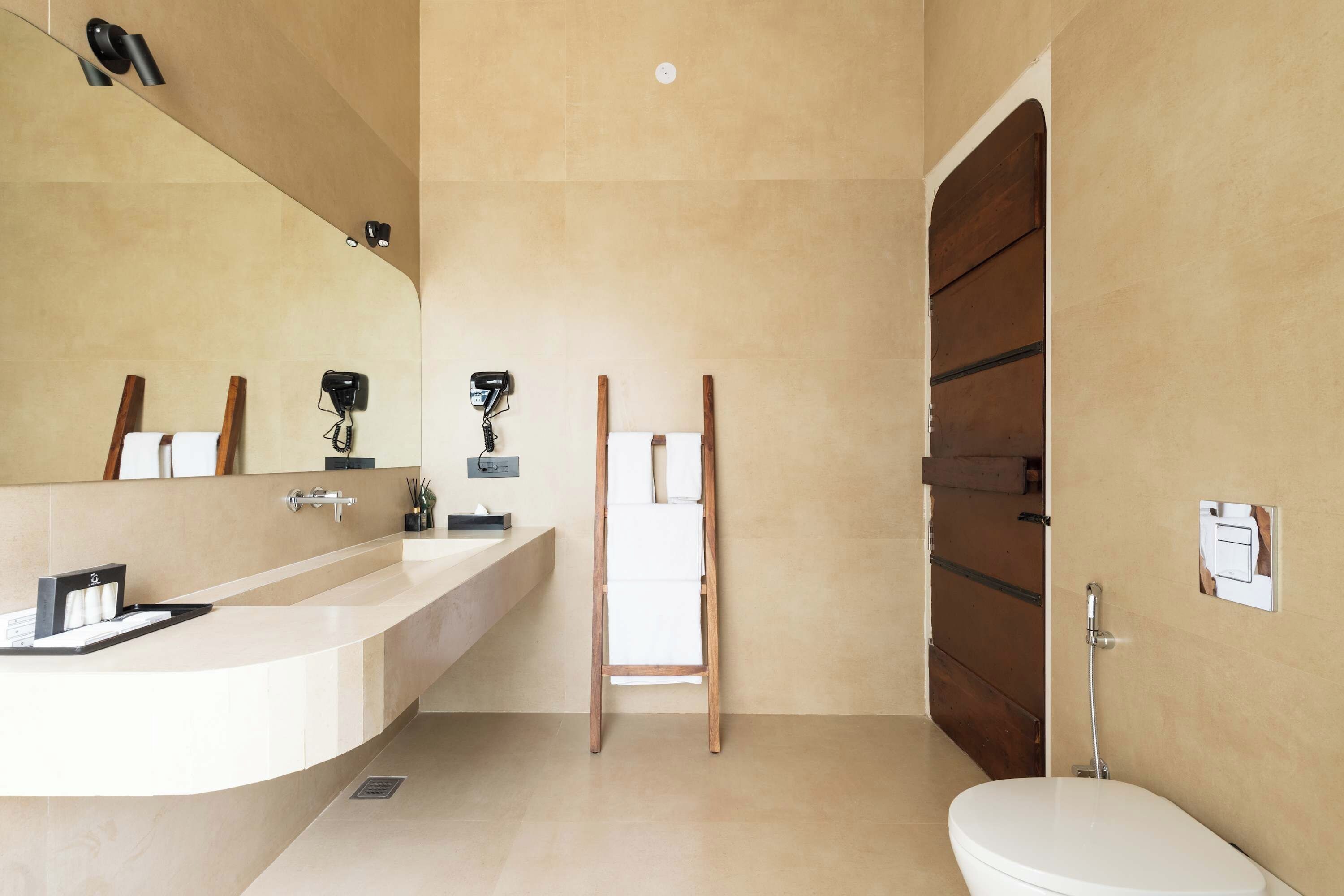 Een moderne badkamer met een grote spiegel, een wastafel en een toilet.
