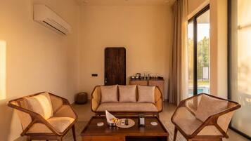 A room with a sofa, two armchairs, a coffee table, and a view of a pool.