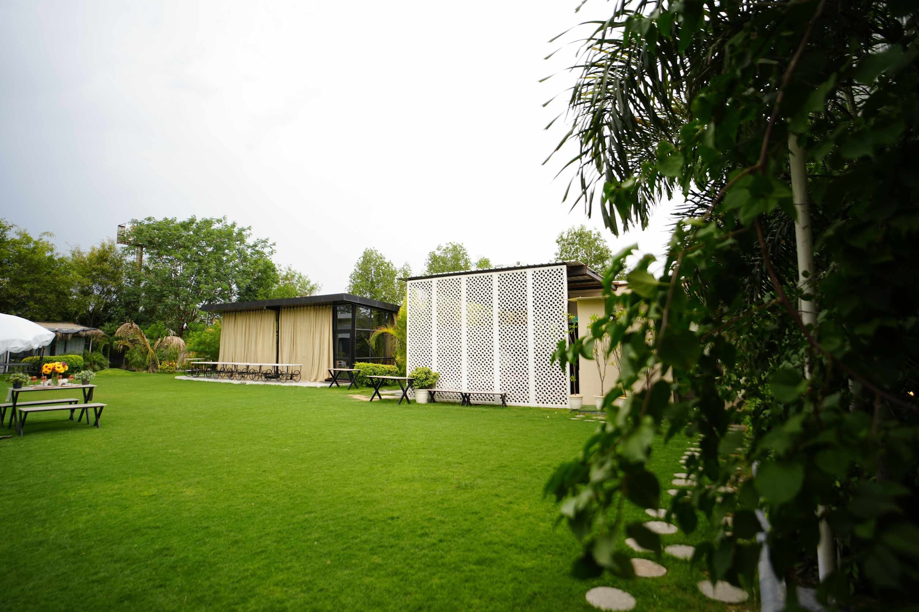 Een verzorgd gazon met picknicktafels en een gebouw met een lattengevel.