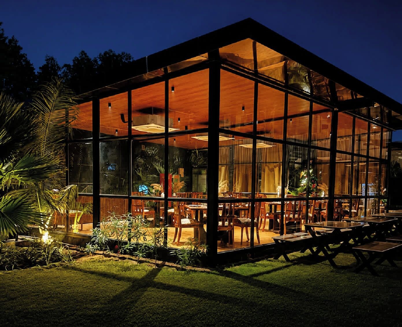 A modern building with a glass facade, wooden interior, and outdoor seating area.