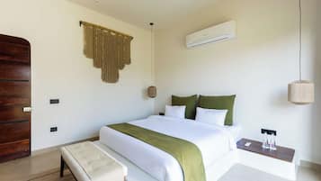 Une chambre à coucher comprenant un lit, une table de chevet, un banc, un climatiseur fixé au mur et une porte en bois.