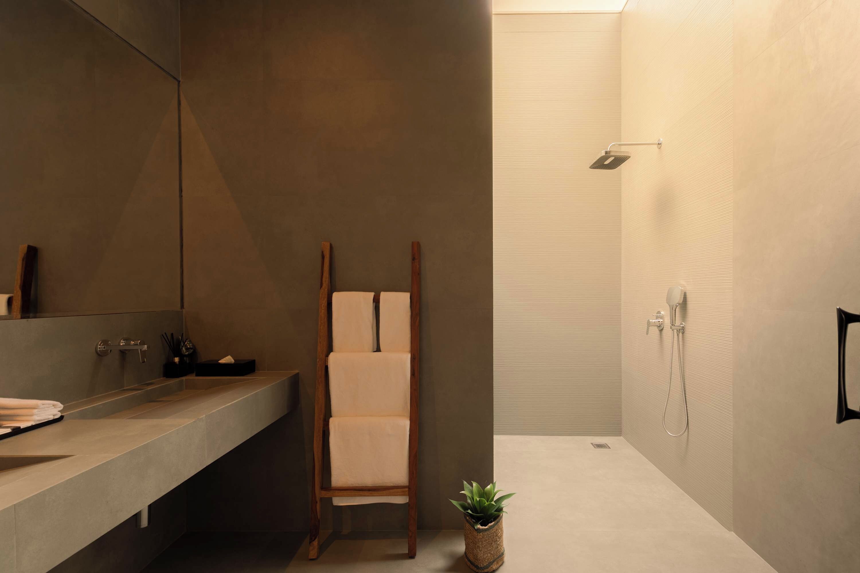 Een moderne badkamer met een grote spiegel, een houten stoel, een wastafel en een douche.