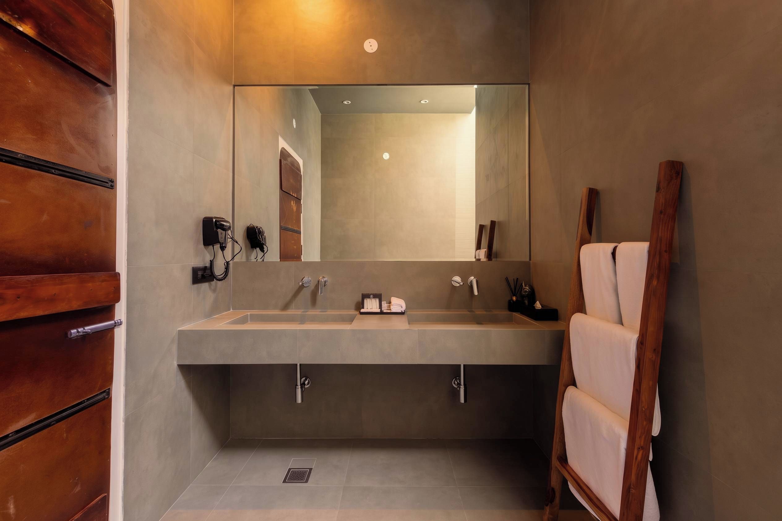 Une salle de bain moderne avec un grand miroir, deux lavabos et un meuble-lavabo en bois.