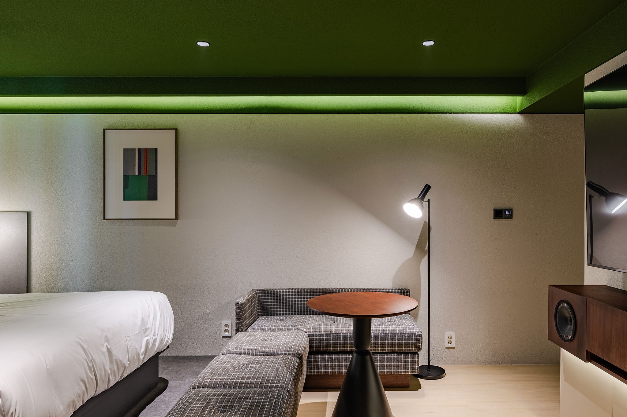 Quarto de hotel moderno com cama, área de estar, mesa e televisão.