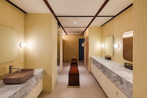 Un baño moderno con dos lavamanos, un tocador, un espejo y un banco.