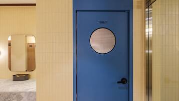 Una puerta azul con un ventanal circular y la palabra 'TOILET' escrita encima.