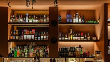 Bar com várias prateleiras repletas de garrafas de bebidas e copos.