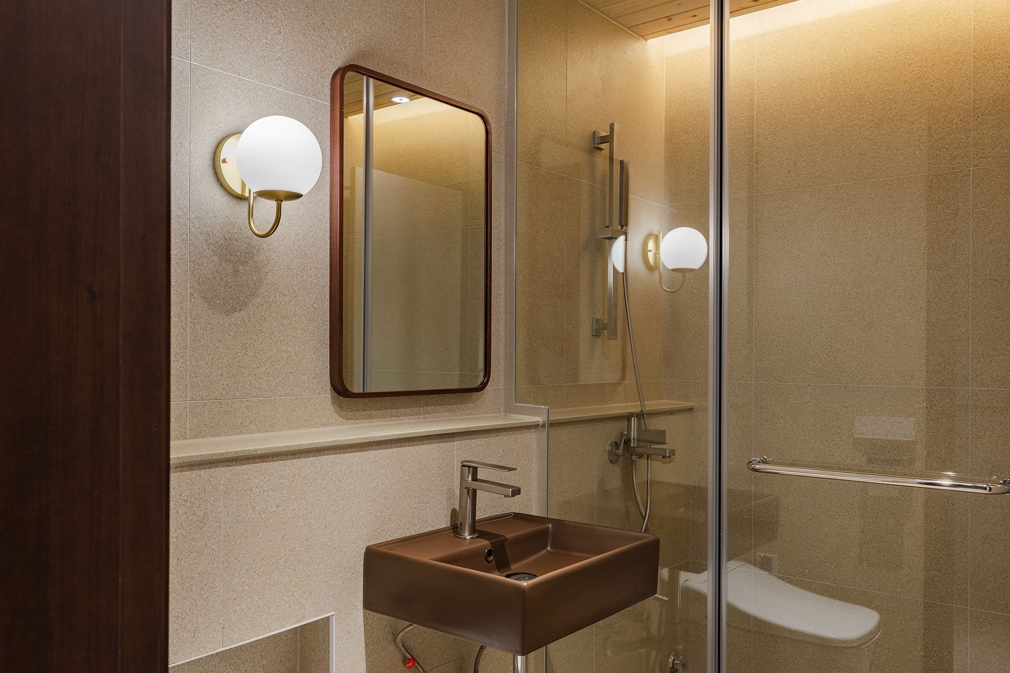 Un baño moderno con cabina de ducha de vidrio, un espejo fijado a la pared y un lavamanos pedestal.