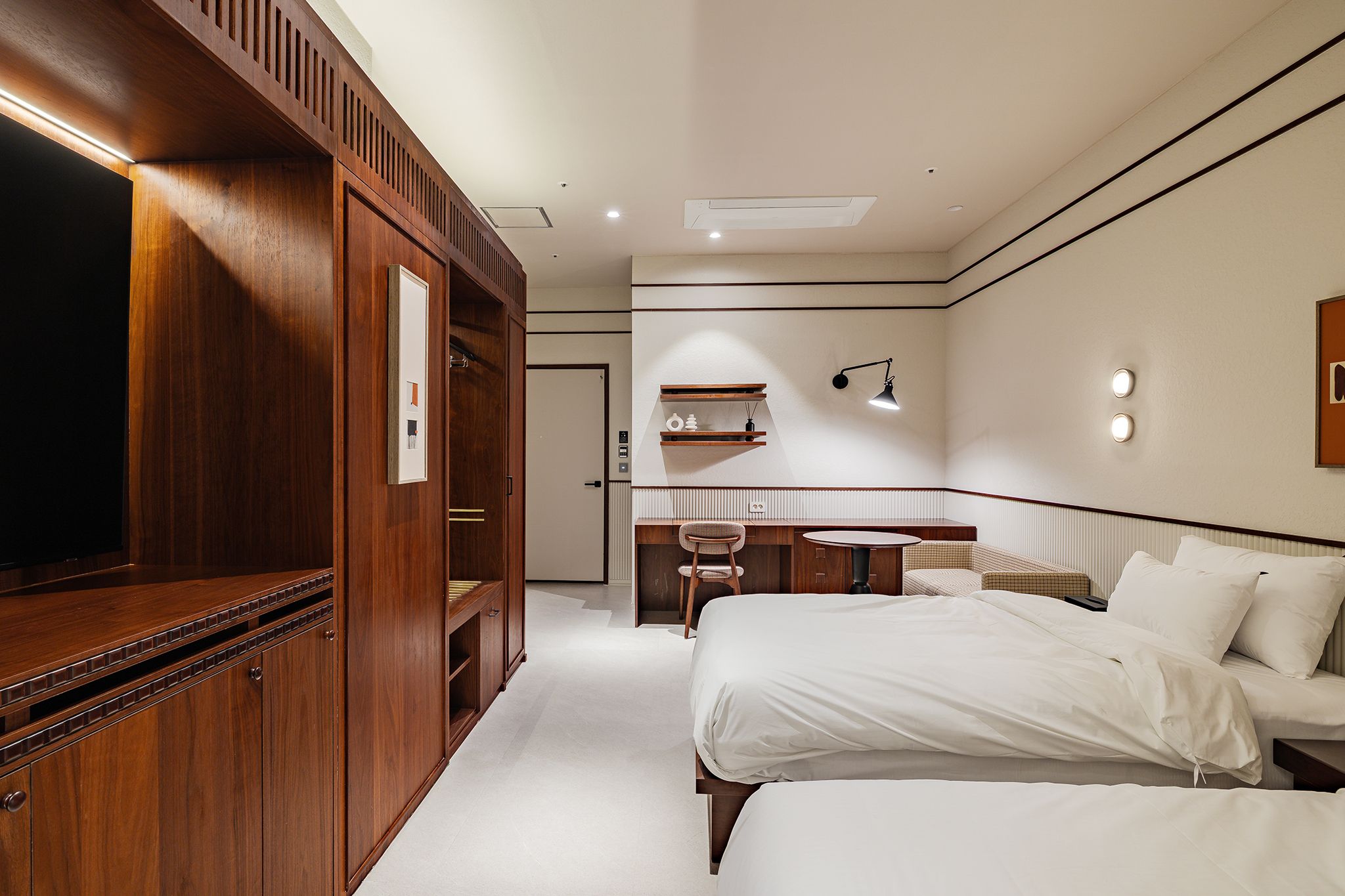 Habitación de hotel con un armario grande, un escritorio con silla, una cama y una pequeña zona de estar.