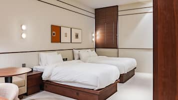 A hotel room with two beds, a round wooden table, and a small seating area.
