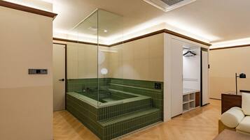 A modern bathroom with a green-tiled jacuzzi, a walk-in closet, and a wooden floor.