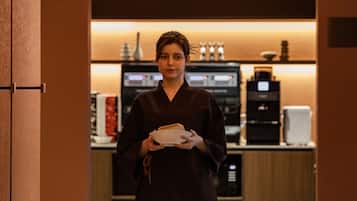 A person holding a plate in a room with a coffee machine and a microwave in the background.